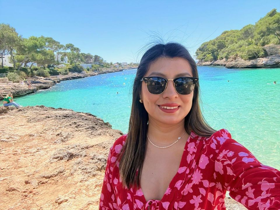 Woman in sunglasses smiling on a sunny coastline, ready to switch from text to video
